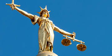 A statue of Lady Justice holding a sword and balancing scales, on top of the Old Bailey, England's criminal court in the City of London, officially called the Central Criminal Court.