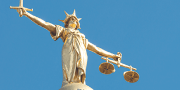 A statue of Lady Justice holding a sword and balancing scales, on top of the Old Bailey, England's criminal court in the City of London, officially called the Central Criminal Court.