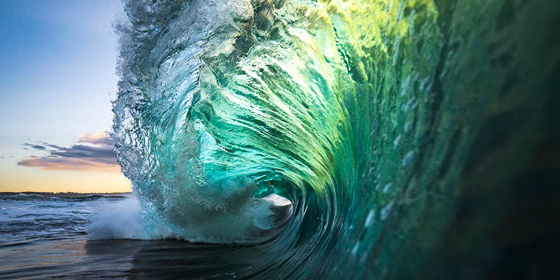 Large colourful wave breaking in ocean over reef and rock