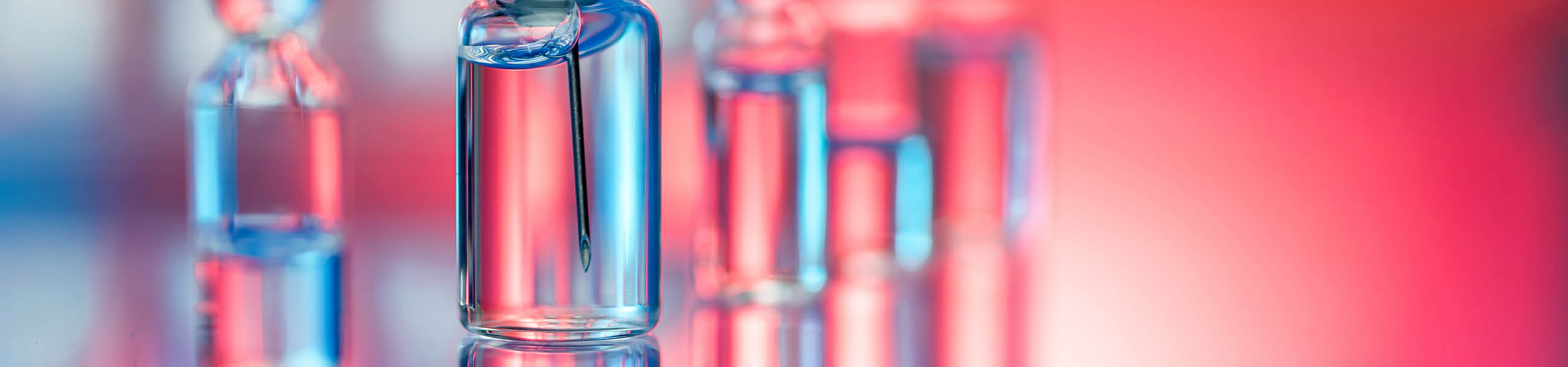 Close up shot of vaccines - glass bottles, ampules and syringe with needle. Good for illustration of flu shot, vaccination and covid-19