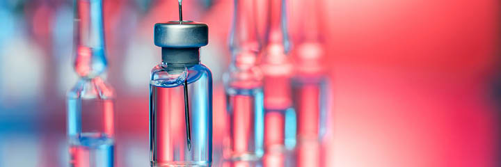 Close up shot of vaccines - glass bottles, ampules and syringe with needle. Good for illustration of flu shot, vaccination and covid-19